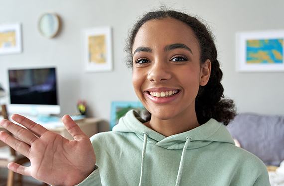 A young girl in a hoodie participating in brand perception surveys by waving her hand in front of a living room.