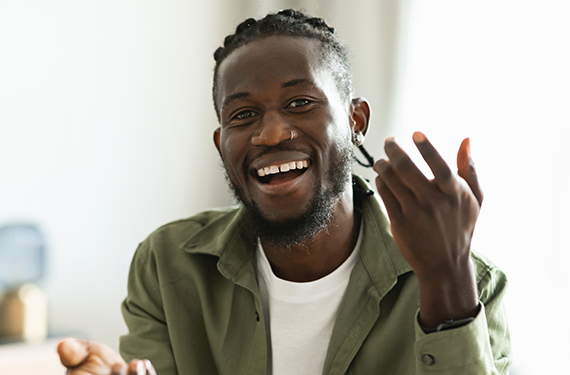 A black man smiling while holding a cell phone for digital prototyping.