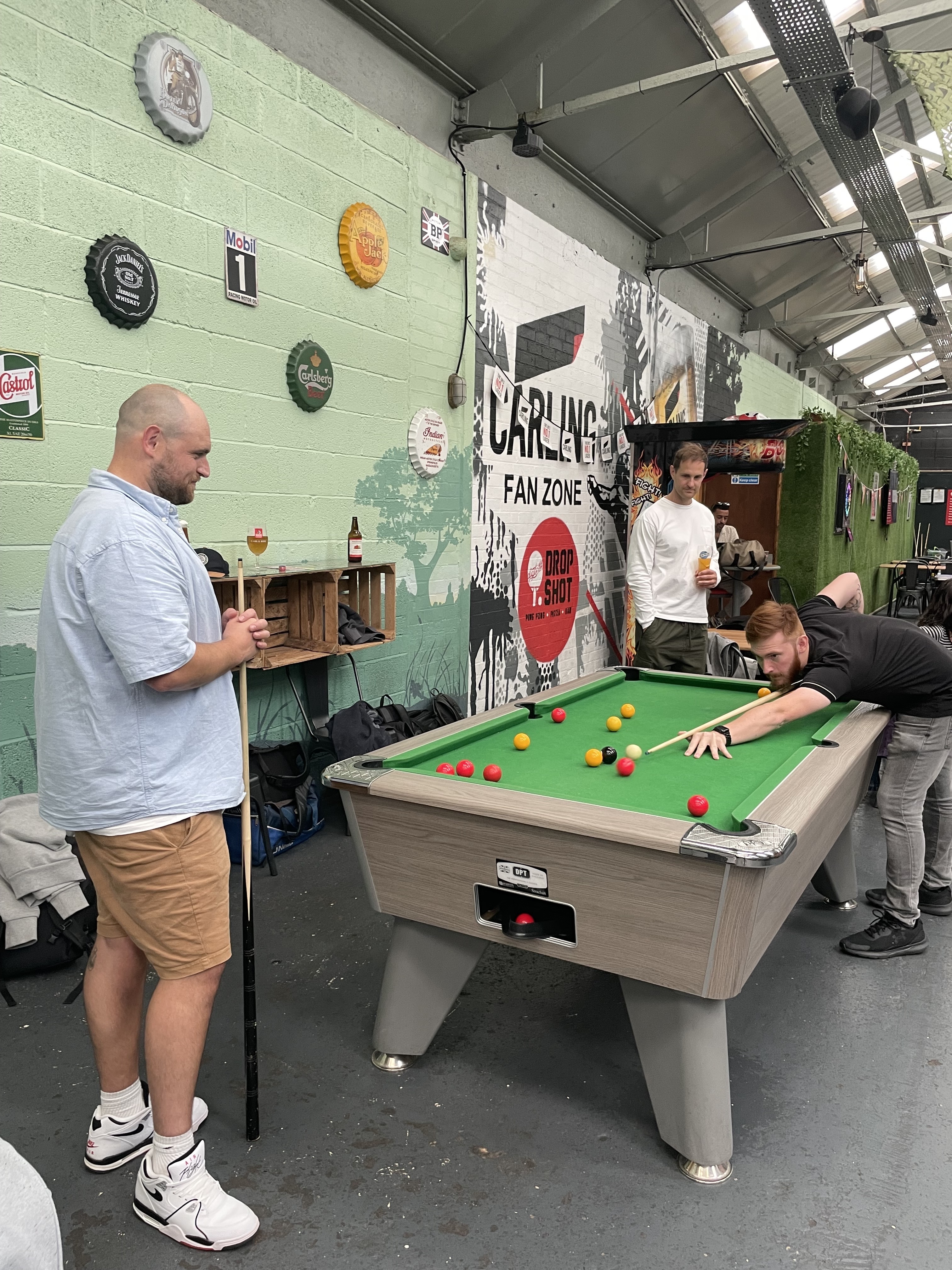 A group of people playing billiards in a warehouse while capturing their experience on Voxpopme.
